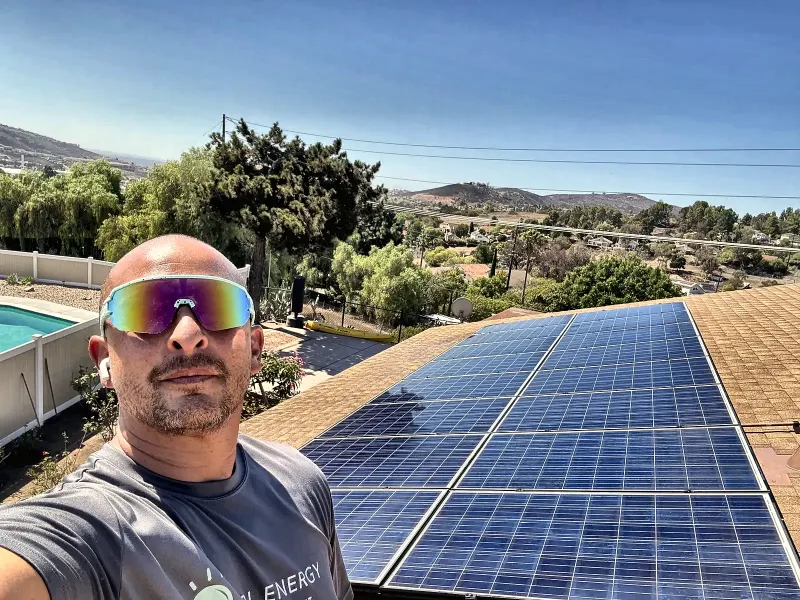 Luis of LTBL Energy on a San Diego County roof next to a solar array his crew reinstalled