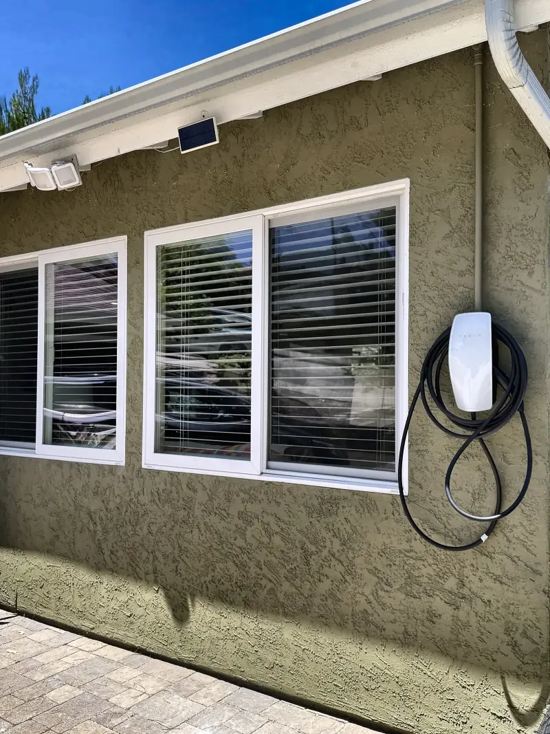 Tesla Wall Connector mounted on an exterior stucco wall at a San Diego home