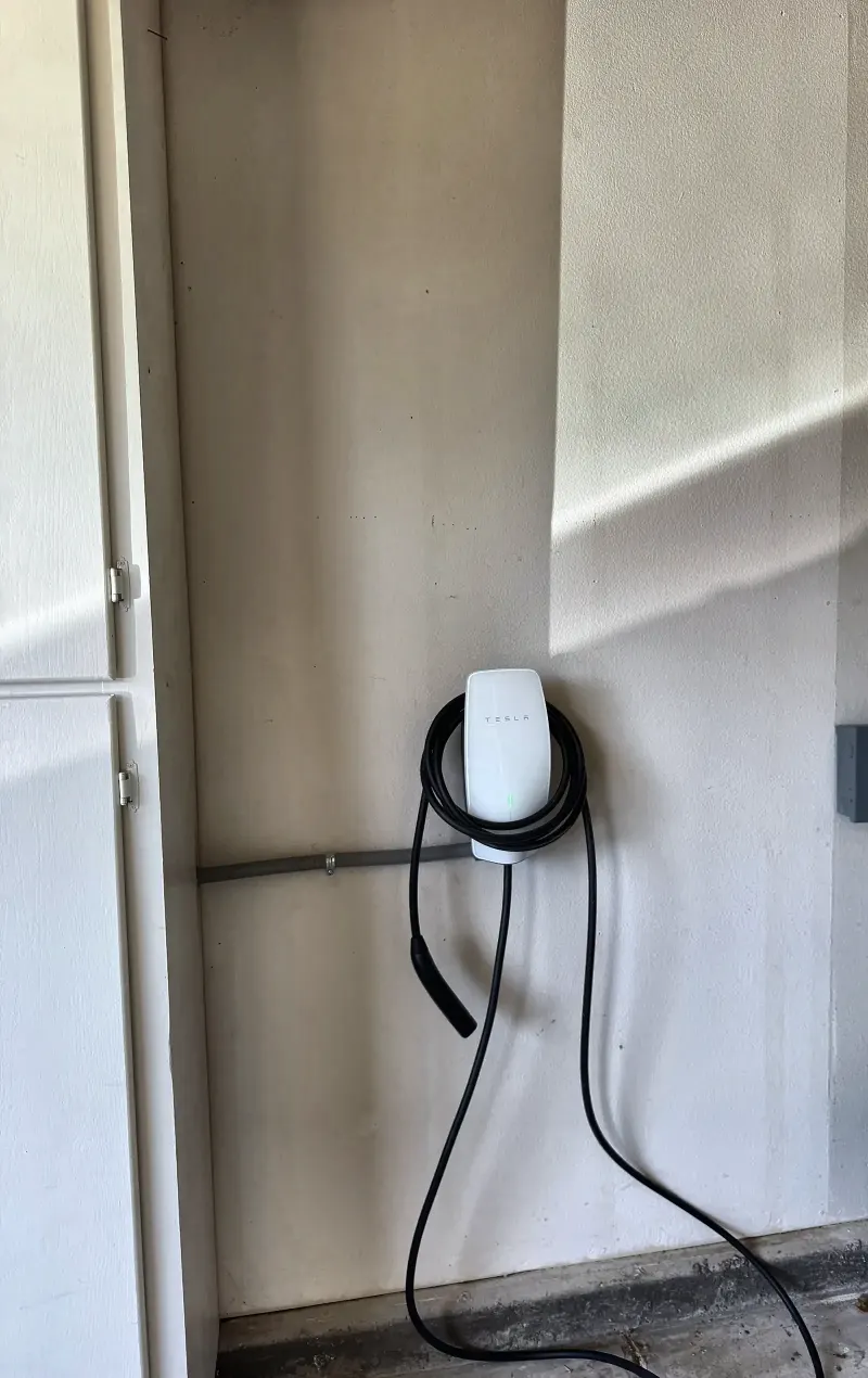 Tesla Wall Connector installed in a San Diego garage with conduit run along the wall