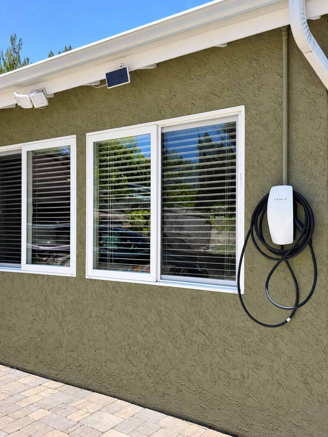Tesla Wall Connector installed outdoors on the exterior wall of a home
