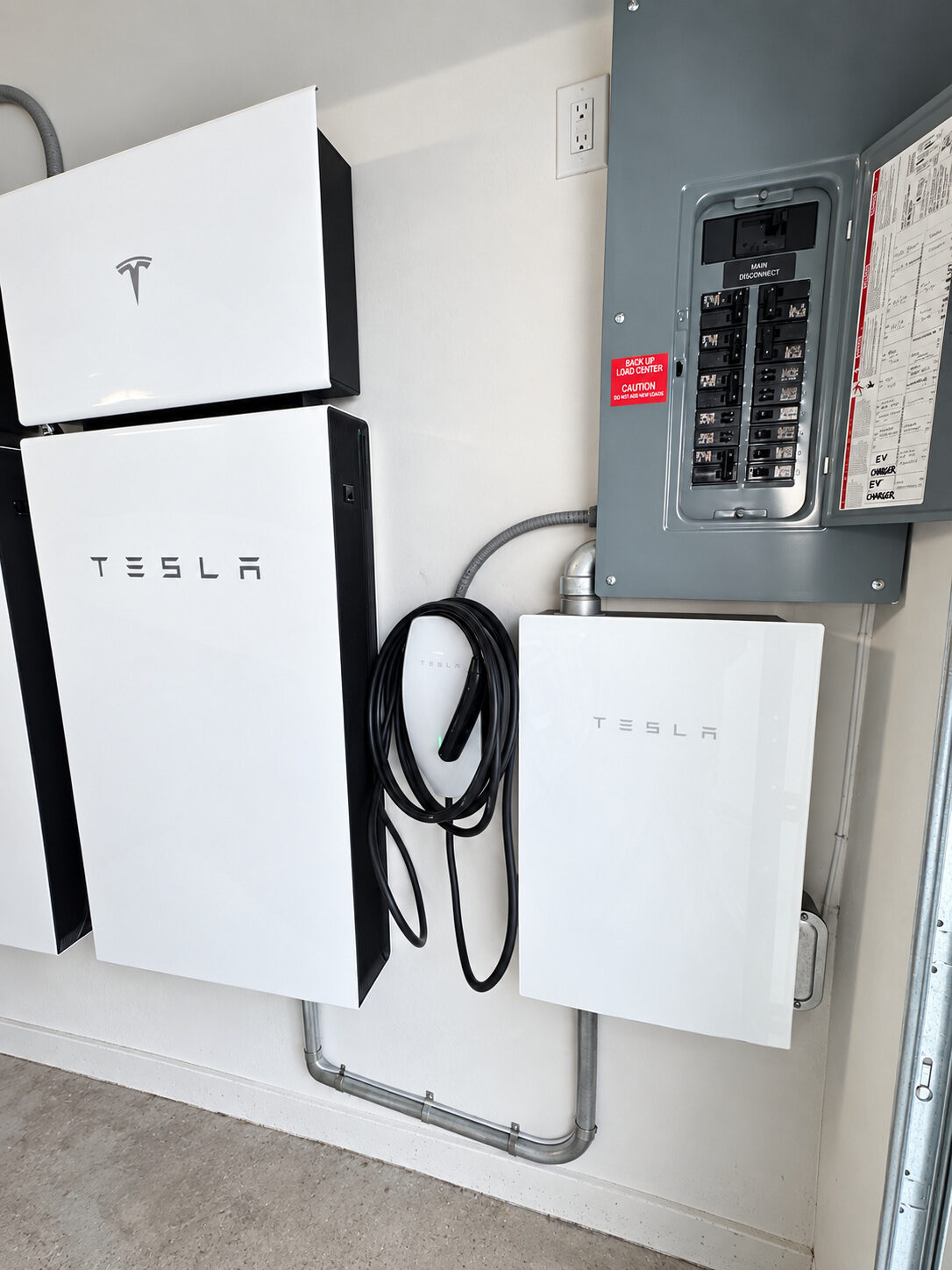 Tesla Wall Connector installed alongside home energy equipment